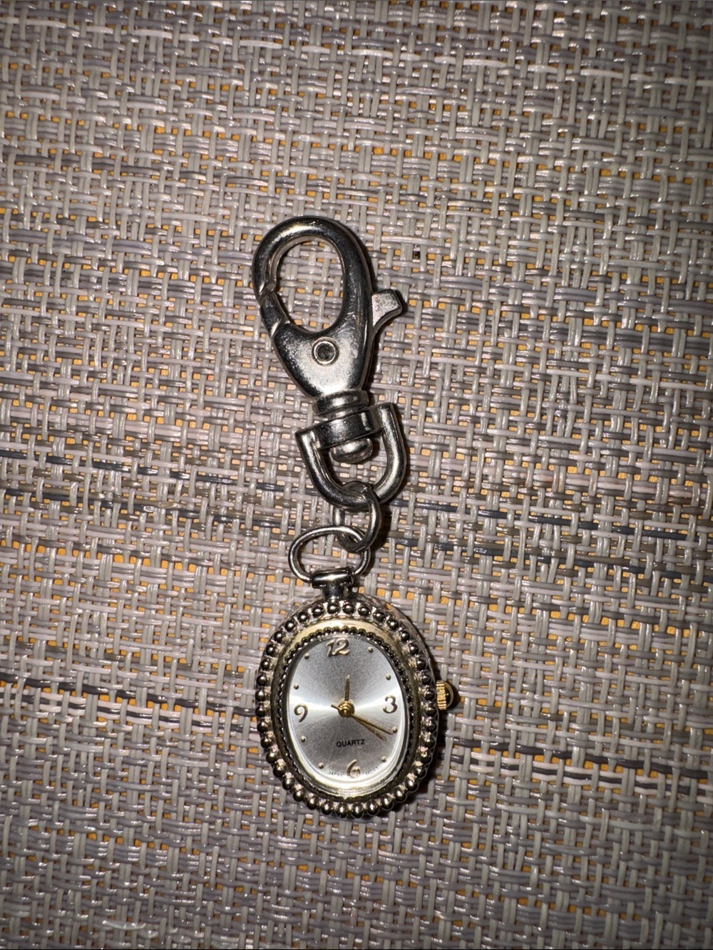 oval quartz watch designed as a charm with a lobster clasp.